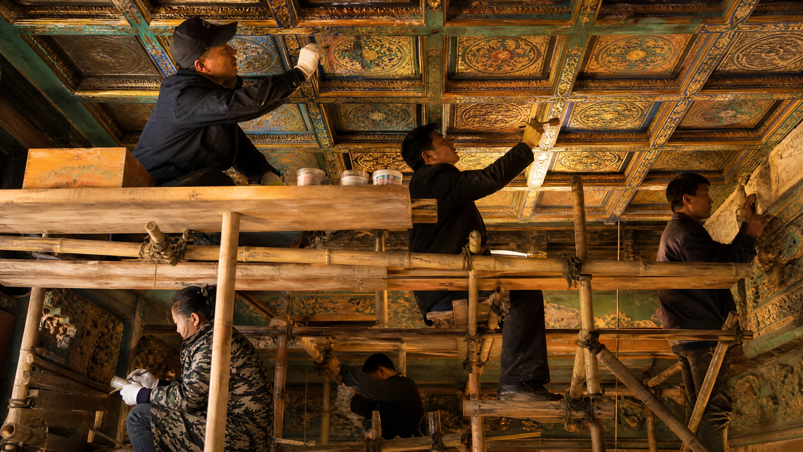 古建筑修复工程现场，工匠在脚手架上修复藻井彩画